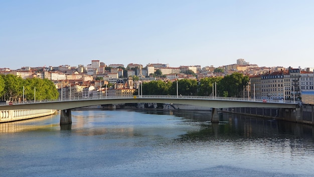 Bridge over river by buildings against clear sky