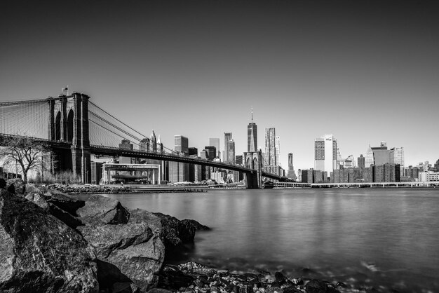 Photo bridge over river by buildings against clear sky