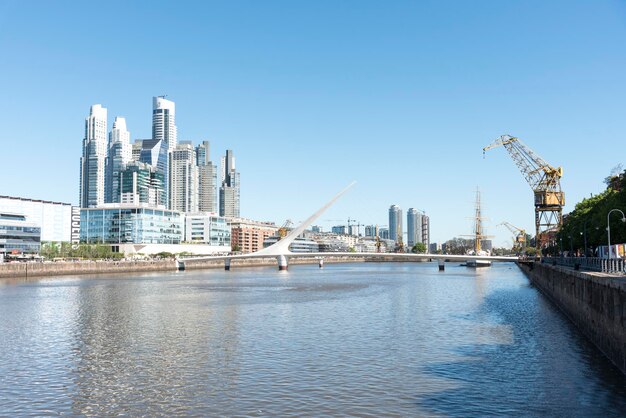 Bridge over river by buildings against clear sky