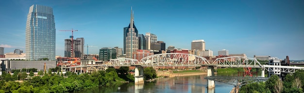 Photo bridge over river by buildings against sky in city