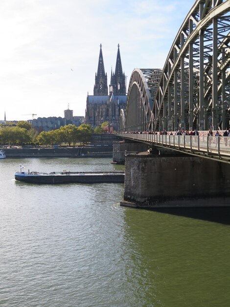 Bridge over river by buildings against sky