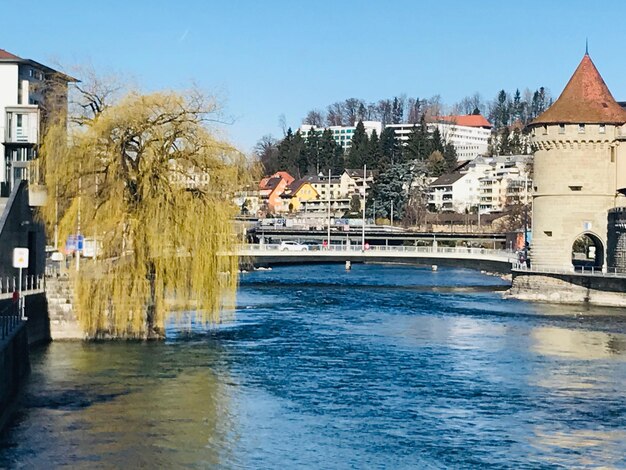 Bridge over river by buildings in city against sky