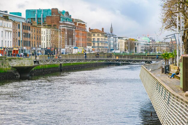 Bridge over river by buildings in city against sky