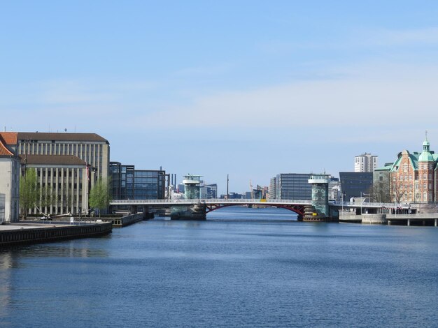 Bridge over river by buildings in city against sky