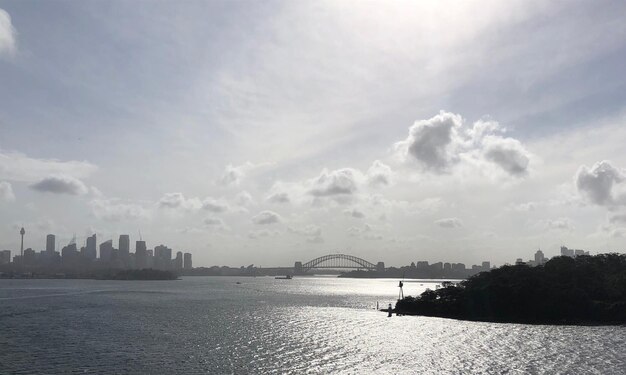 Photo bridge over river by buildings in city against sky