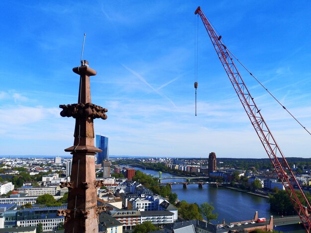 Bridge over river by cityscape against sky