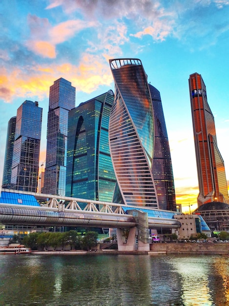bridge over river by modern buildings against sky in city