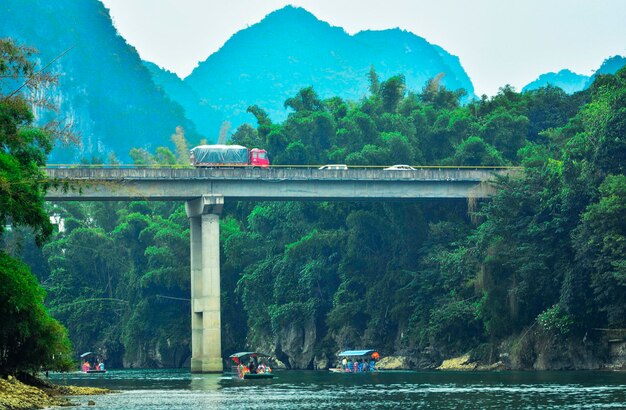 Bridge over river by trees against mountains