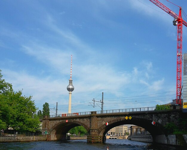 Bridge over river in city against cloudy sky