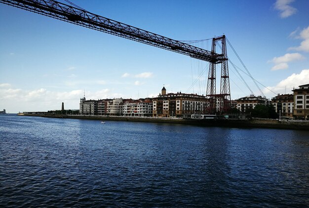 Bridge over river in city against sky