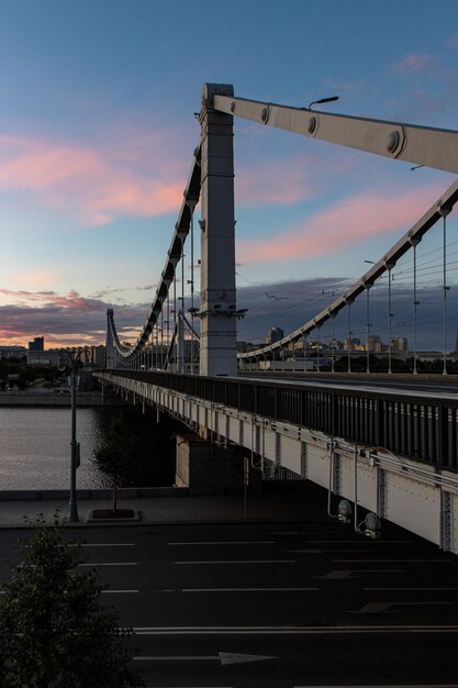 Photo bridge over river in city against sunset sky