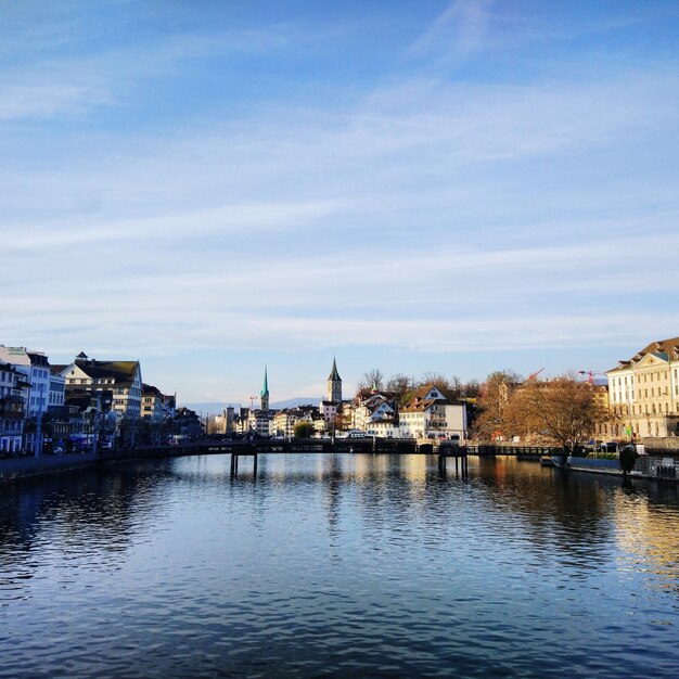 Photo bridge over river with buildings in background