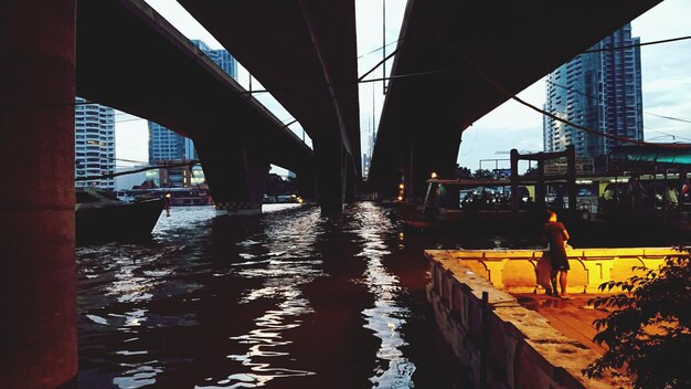 Photo bridge over river with city in background