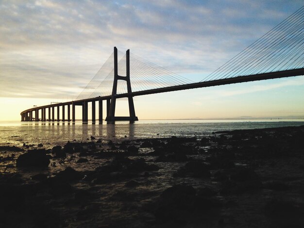 Bridge over sea against sky during sunset