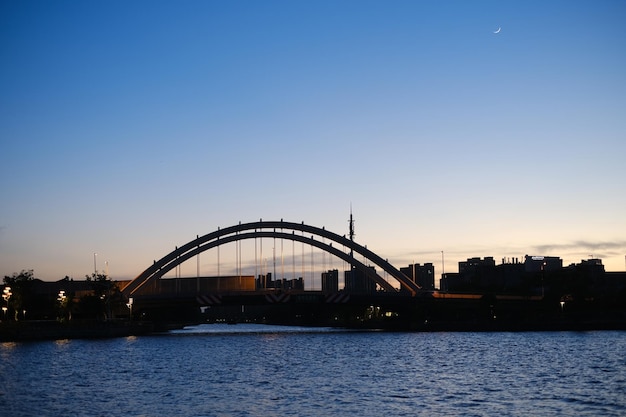 A bridge over the water with a moon in the sky