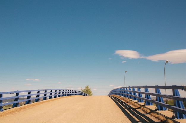 A bridge with blue railings and a cloud in the sky