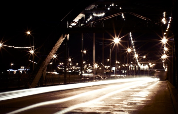 A bridge with lights on and a car driving under it