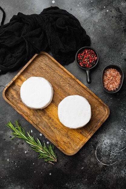 Brie cheese on black dark stone table background top view flat lay