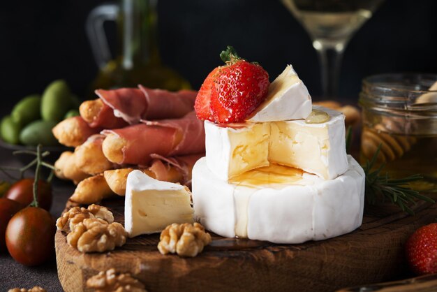 Foto brie, camembert, grissini, jamon, vino, noci, miele. spuntini per il vino. snack italiani, primo piano