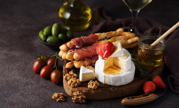 Brie cheese, camembert, grissini, jamon, wine, nuts, honey. Snacks for wine. Italian snacks