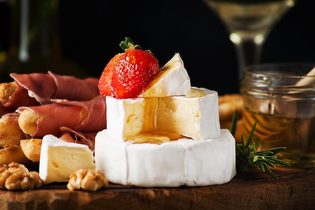 Formaggio brie, camembert con miele e fragole, grissini, noci - spuntino tradizionale italiano, fuoco selettivo