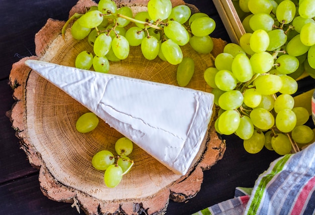 Brie cheese and white fresh grapes on a wooden board