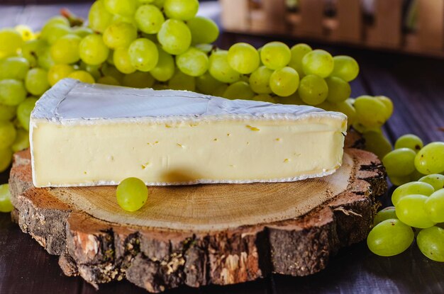 Brie cheese and white fresh grapes on a wooden board