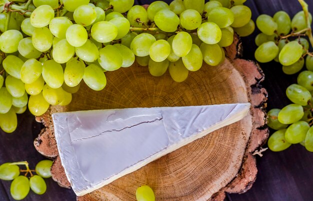 Brie cheese and white fresh grapes on a wooden board