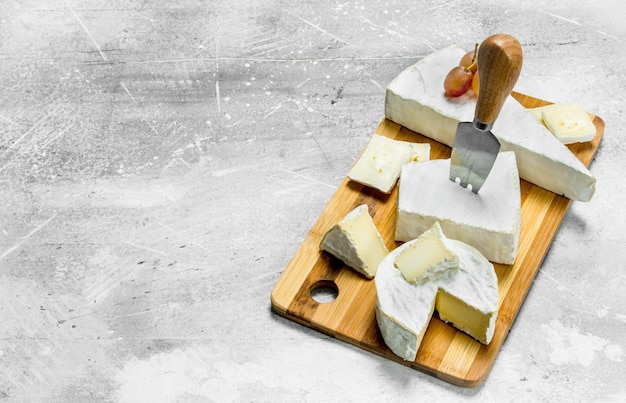 Photo brie cheese with grapes on a wooden board