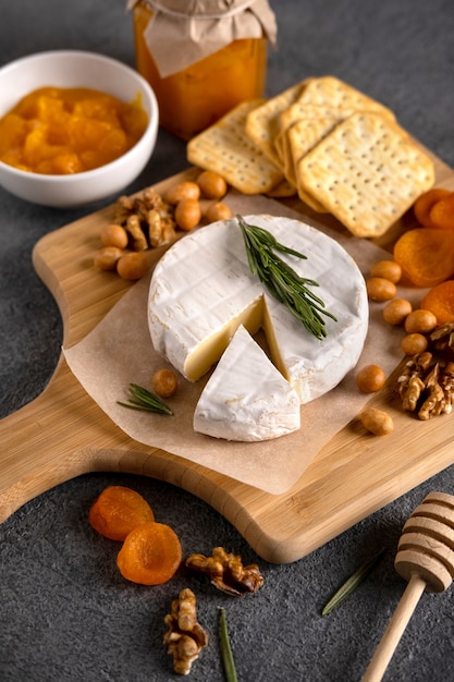 Brie cheese with nuts, pear slices and dried apricots. Camembert cheese. Brie cheese or Camembert cheese  on a wooden board. Tasty cheese starter.