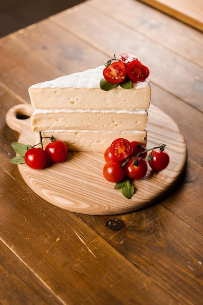 Brie cheese with tomatoes on the wooden plate in cheese store Creative idea for advertising a cheese shop