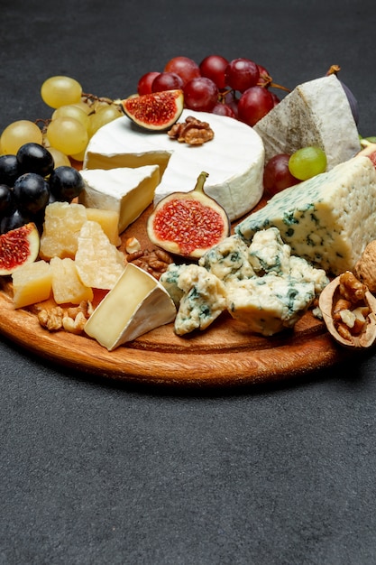 Brie cheese on a wooden Board with fresh figs and grapes
