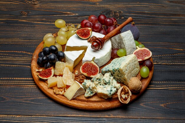 Brie cheese on a wooden Board with fresh figs and grapes