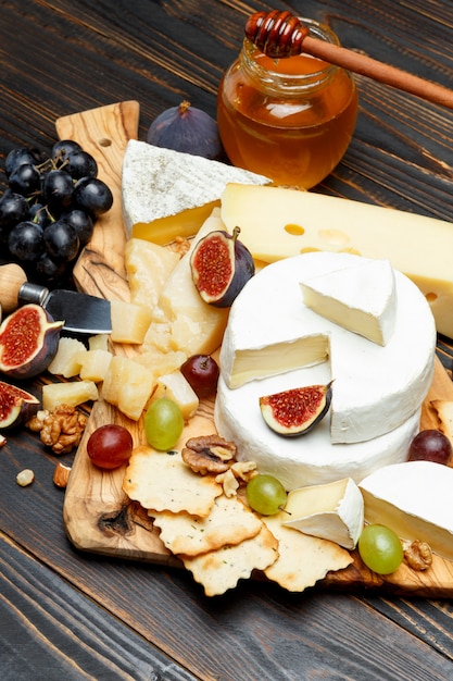 Brie cheese on a wooden Board with fresh figs and grapes