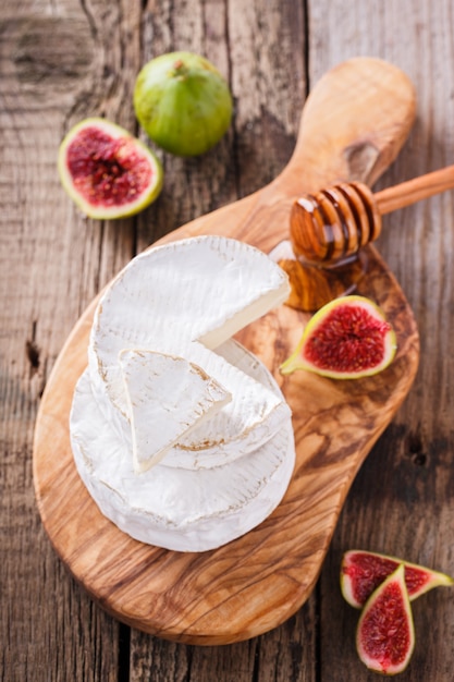 Brie cheese on a wooden Board with fresh figs and honey