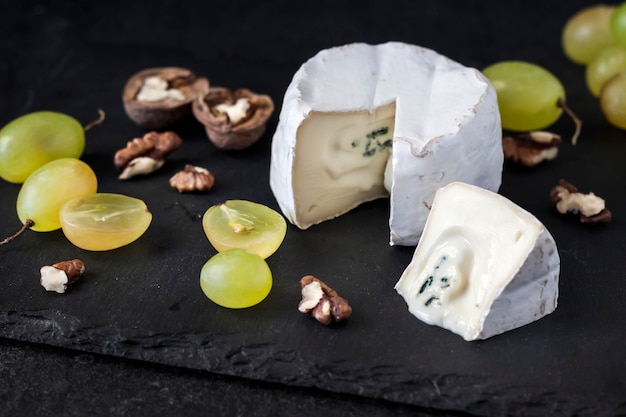 Brie soort kaas. zachte kaas met druiven en walnoten op zwarte achtergrond