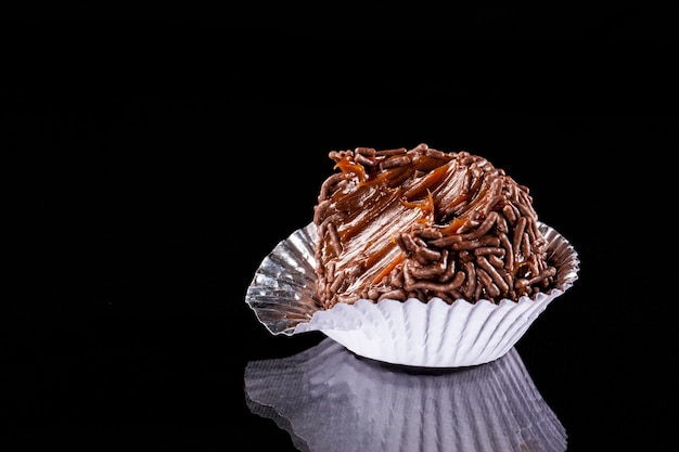 Brigadeiro bitten, a brazilian sweet, on a black background.