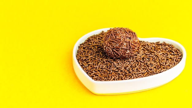 Brigadeiro in heart shaped bowl on yellow background