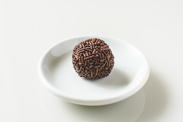 Brigadeiro, dolce brasiliano tradizionale, su un piatto, fondo bianco.