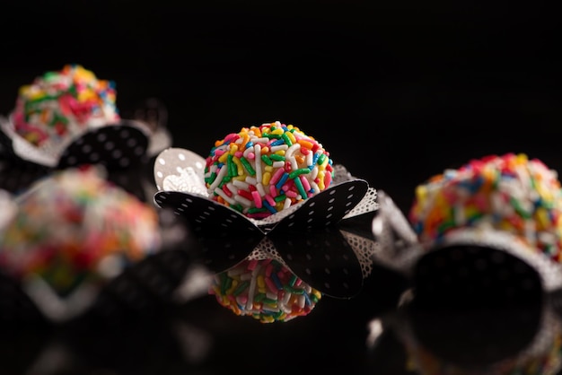 Brigadeiros beautiful colorful sweets on black reflective surface selective focus