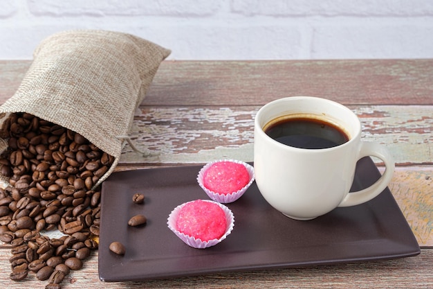 Brigadeiros bichos de pe next to a cup and coffee beans (side view).