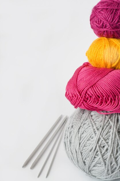 Bright balls of yarn and knitting needles lying on a white background