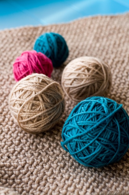 Bright balls of yarn lying on beige knitted plaid