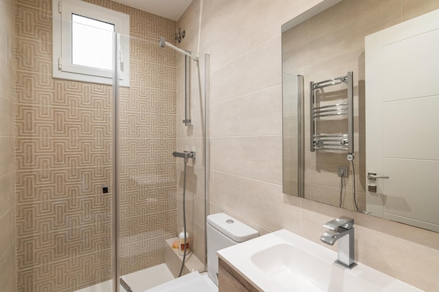 Bright bathroom in beige colors with glossy ceramic tile walls and lighting the bathroom has a