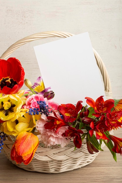 Foto bellissimi fiori luminosi in un cestino con una cartolina con un posto per la tua iscrizione