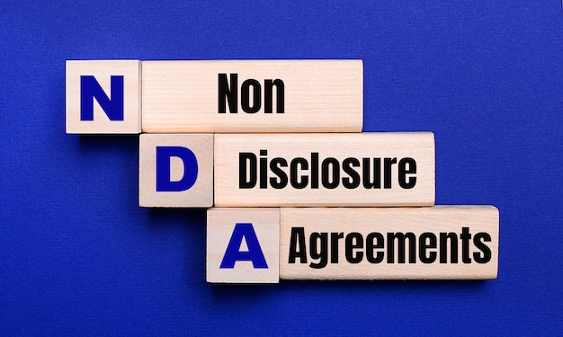 NDA Non Disclosure Agreements라는 텍스트가 있는 밝은 파란색 배경의 밝은 나무 블록 및 큐브