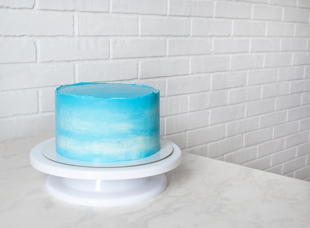 コピースペースのあるスタンドに明るい青いケーキ。クリームケーキの雲のパターン。