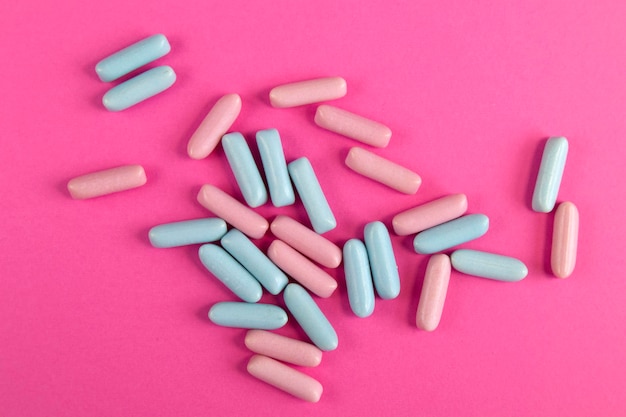 Bright blue and pink colorful candies scattered on bright pink background