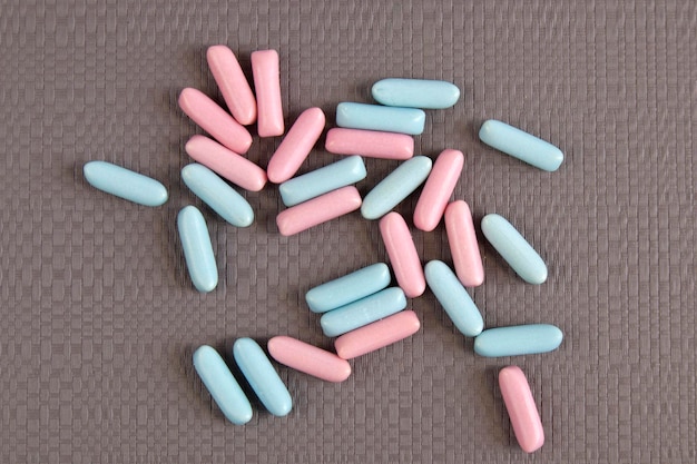 Bright blue and pink colorful candies scattered on grey textured background