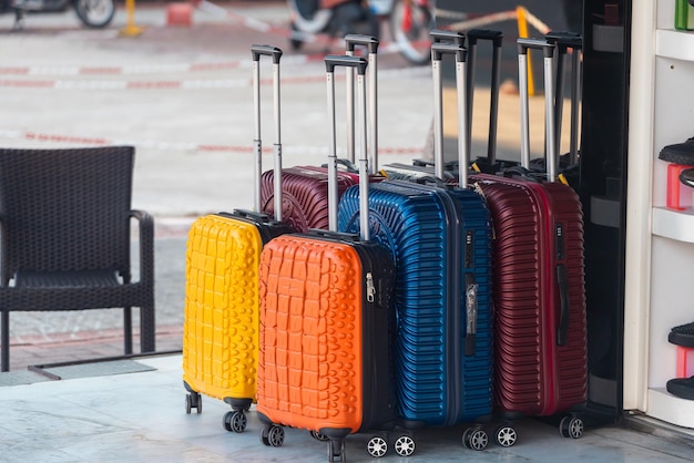 Bright blue red yellow and orange rows of suitcases with extended handles and different sizes are on sale in front of the store